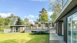 A modern house with a deck, a small shed, and a large windowed room. - 4 bedroom beautiful home in Knebel (Knebel)