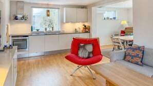 A modern kitchen with white cabinets, a built-in oven, and a window with a view of trees. - 4 bedroom beautiful home in Knebel (Knebel)