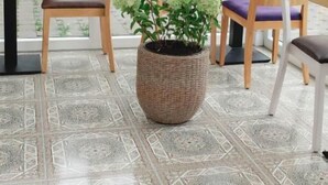 Un espace intérieur accueillant avec des chaises et des tables en bois, un grand panier tressé rempli de plantes et un sol à motifs.