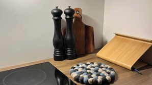 Une cuisine dotée d’une plaque de cuisson à induction noire, d’une planche à découper en bois et d’un tapis rond à texture particulière.