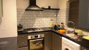 Une cuisine compacte équipée d’une cuisinière à gaz, d’un four et d’un lave-vaisselle encastré.