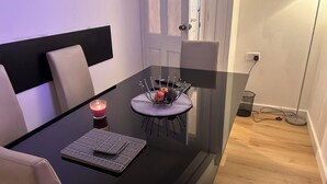Un espace repas moderne avec une table en verre, une bougie et un présentoir à fruits.