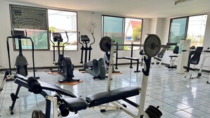 Een fitnessruimte met diverse trainingsapparaten, waaronder loopbanden, hometrainers en krachttoestellen.