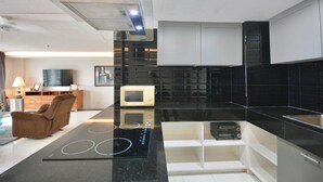 A modern kitchen with a black countertop, built-in microwave, and a glass backsplash. - One-Bedroom Sea-View Condo, 17th Floor – Angket, Jomtien (Muang Pattaya)