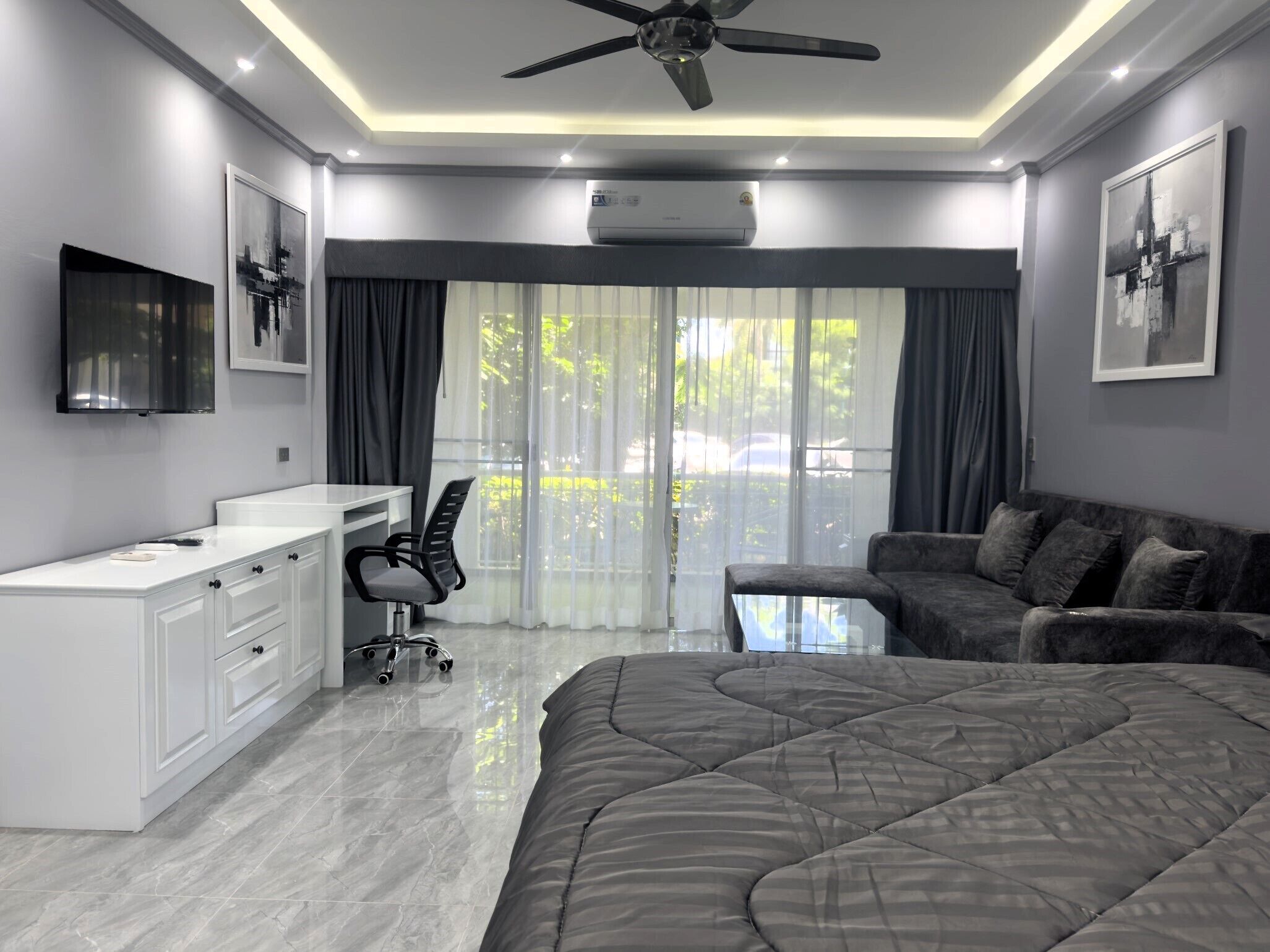 Quarto moderno com uma cama grande, uma escrivaninha, uma cadeira e um sofá.