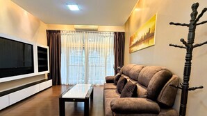 Ein Wohnzimmer mit Flachbildfernseher, einer Couch, einem Couchtisch und einem Garderobenschrank.