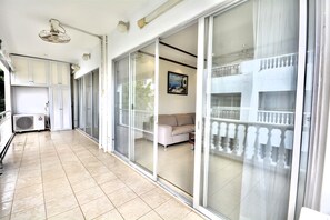 En rummelig balkon med en skydedør til en opholdsstue, en aircondition og en loftsvifte.
