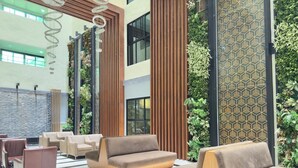 Un vestíbulo moderno con suelo a cuadros, bancos de madera y jardines verticales.