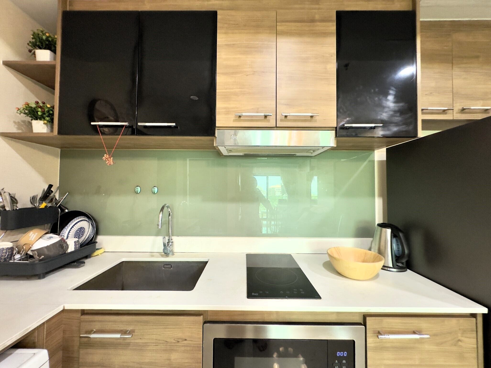 A modern kitchen with black and wooden cabinets, a stainless steel sink, and an induction cooktop.