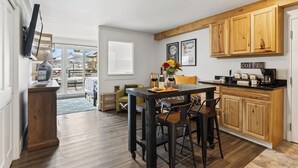Una cocina moderna con armarios de madera, una zona de comedor con taburetes de bar y vistas a una montaña nevada.