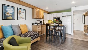 Un apartamento moderno con cocina, comedor y sala de estar con sofá y sillón verde.