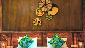 A hotel room with a wooden headboard, two pillows with abstract designs, and a wall with circular wall art. - Noora Resort (Bishoftu)