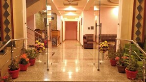 A hotel lobby with a marble floor, a reception desk, a sofa, and potted plants. - Hotel Golden Eye (Srinagar)