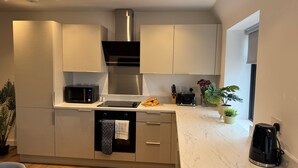 Una cocina moderna con armarios blancos, una campana de acero inoxidable, microondas, tostadora y cafetera.