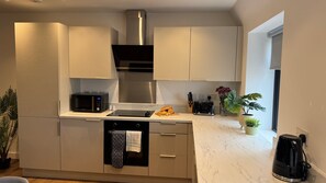 Eine moderne Küche mit weißen Schränken, einer Edelstahl-Dunstesse, einer Mikrowelle, einem Toaster und einer Kaffeemaschine.