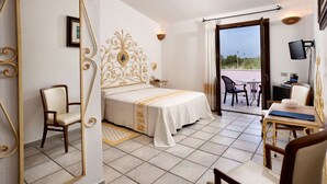 Habitación de hotel con cama, una silla, escritorio y balcón con sillas.