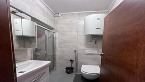 A compact bathroom with a glass shower enclosure, a white sink, and a toilet.