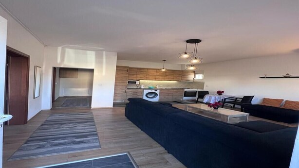 A modern living space with a kitchen, a sofa, a dining area, and a hallway.