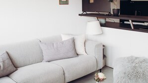 Un salon moderne avec un canapé, un pouf et une petite table sur laquelle est posé un vase.