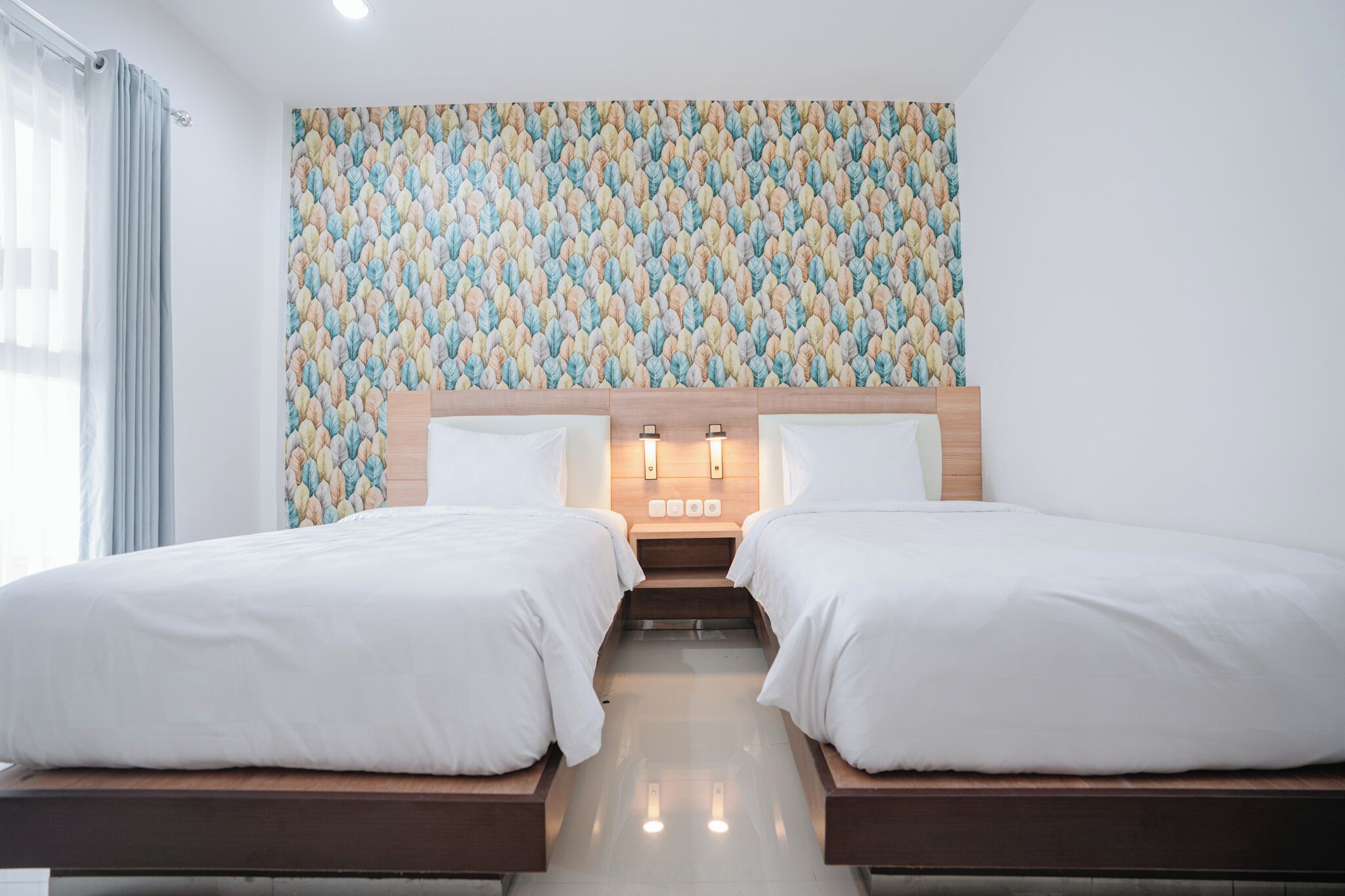 A hotel room with two beds, a patterned wall, and a modern design.