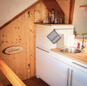 Una cucina con pareti in legno, un lavello e un bollitore sul piano di lavoro.