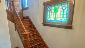 A wooden staircase with decorative balusters and a stained glass window with geometric patterns.