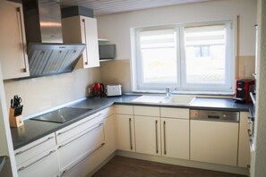 A modern kitchen with a stainless steel range hood, a built-in microwave, a sink, and a window with a view. - Design Apartment "Modern Times" – Central & Quiet (Schluchsee)