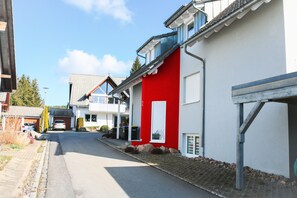 A residential street with houses, including one with a red facade and a garage. - Design Apartment "Modern Times" – Central & Quiet (Schluchsee)