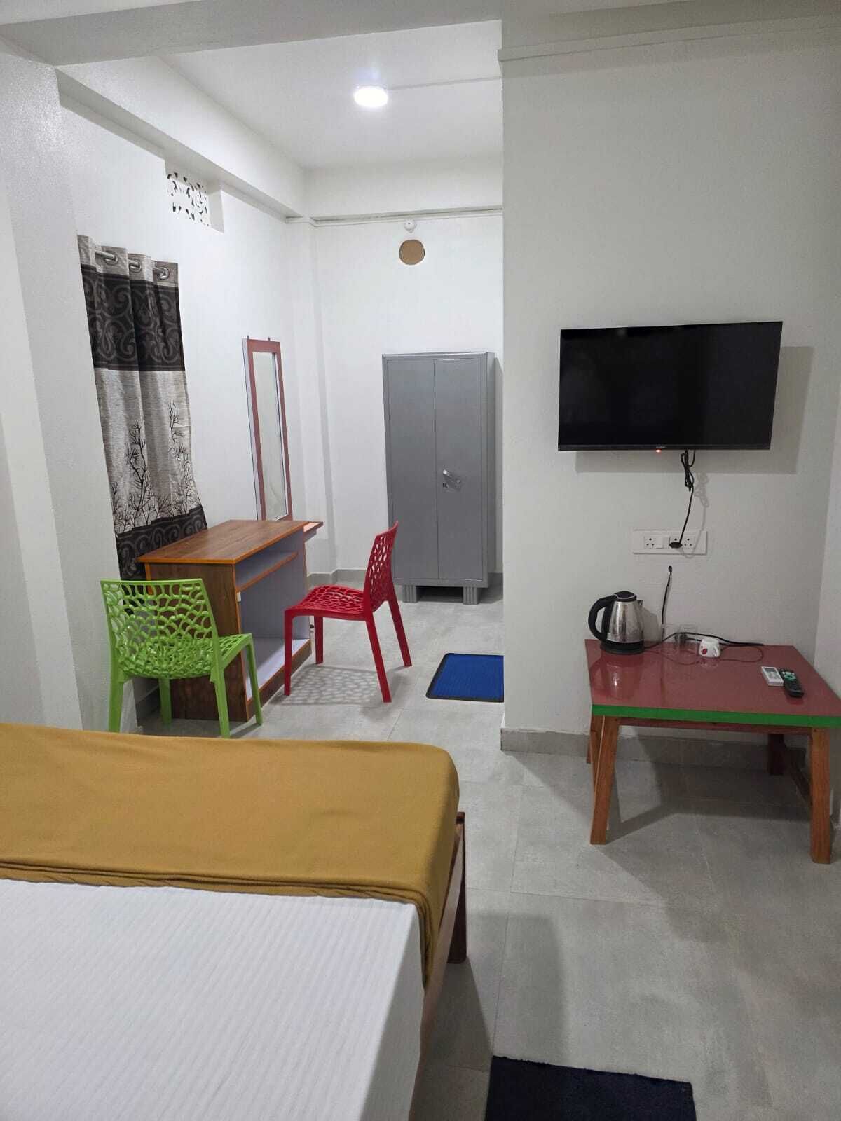 Een hotelkamer met een bed, een bureau met stoel, een televisie en een kledingkast.