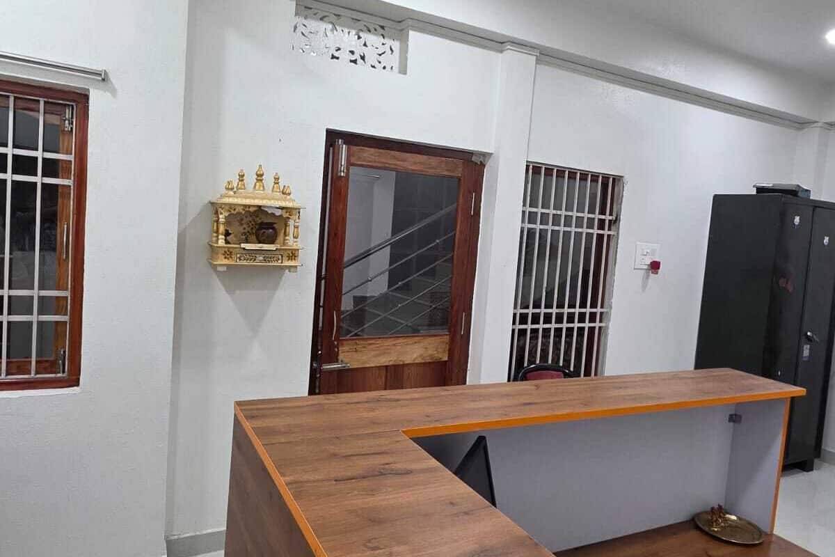 A room with a wooden reception desk, a ceiling fan, and a door with a decorative panel.
