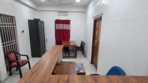 A conference room with a long wooden table, two chairs, a small cabinet, and a door.