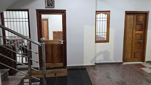 A hallway with a staircase, wooden doors, and a small window.