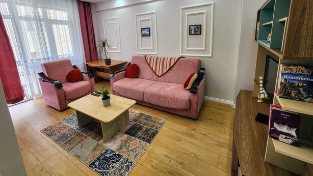 Una sala de estar con dos sofás rosas, una mesa de centro y una estantería.