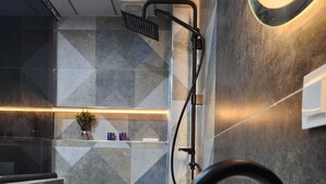 Un baño moderno con un lavabo blanco, grifo negro y ducha de diseño curvo.