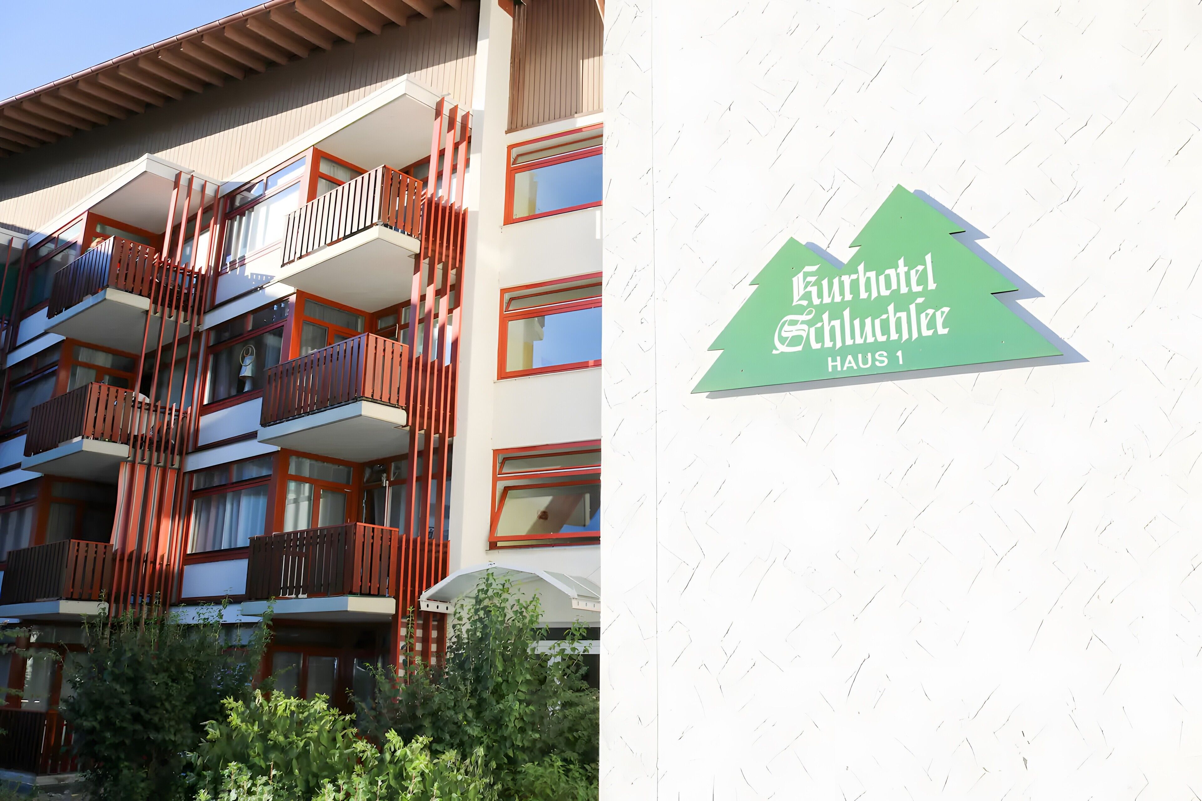 Un edificio de varios pisos con balcones y un cartel que indica 'Kurhotel & Schutzhütte Haus 1'.
