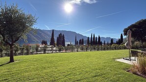 A well-maintained grassy area with a bench, a sculpture, and a clear view of mountains and a lake in the background. - Villa Carmel (Tremezzo)