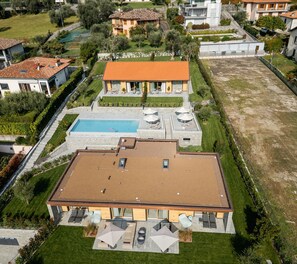 Vista aérea de una propiedad residencial con piscina, patio cubierto y césped cuidado.