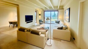 A modern living room with a large sofa, a smaller sofa, a TV, and a dining area. - Villa Carmel (Tremezzo)