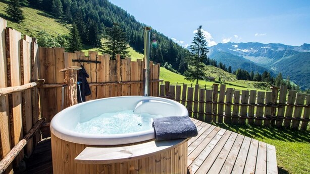 Un jacuzzi en una terraza de madera con vista a la montaña.