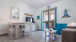 Uma sala de estar com área de jantar, televisão, sofá e mesa.