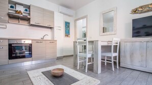 Uma cozinha moderna com forno embutido, armários brancos e um espaço de refeições com mesa e cadeiras.