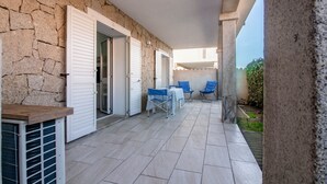 Uma área externa coberta com paredes de pedra, uma mesa com cadeiras e vista para o exterior.