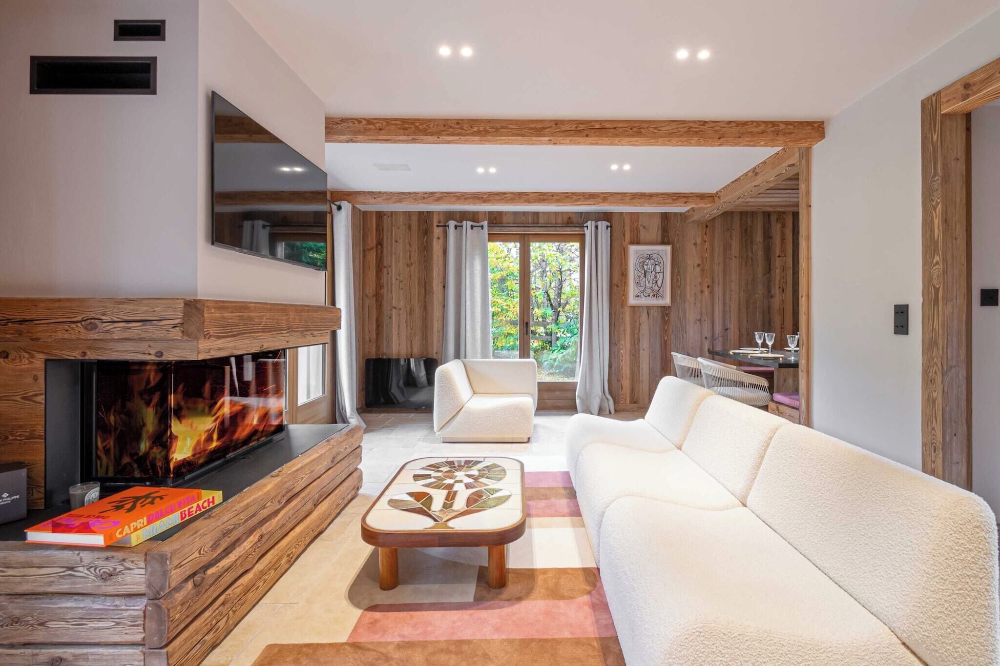 A modern living room with a fireplace, white sofas, a coffee table, and a dining area with a table and chairs.