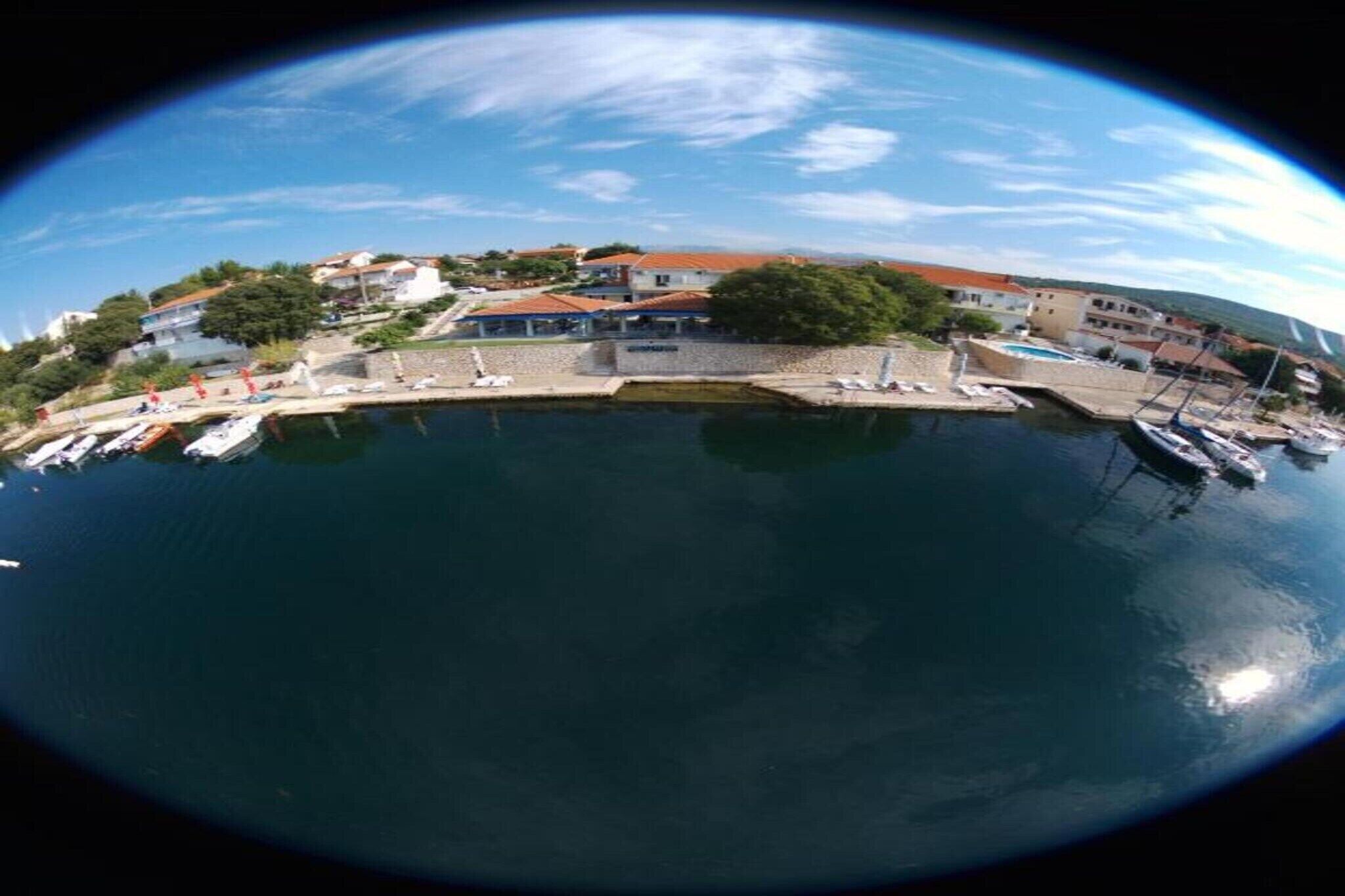 Une ville côtière dotée d’un port de plaisance, de bâtiments aux toits rouges et d’un ciel dégagé.