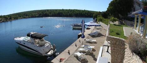 A marina with boats docked, a stone wall, and a building with a covered area.