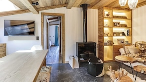 Una sala de estar acogedora con chimenea, estanterías de madera y un televisor montado en la pared.