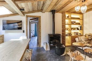 Een gezellige woonkamer met een open haard, houten planken en een aan de muur bevestigde televisie.