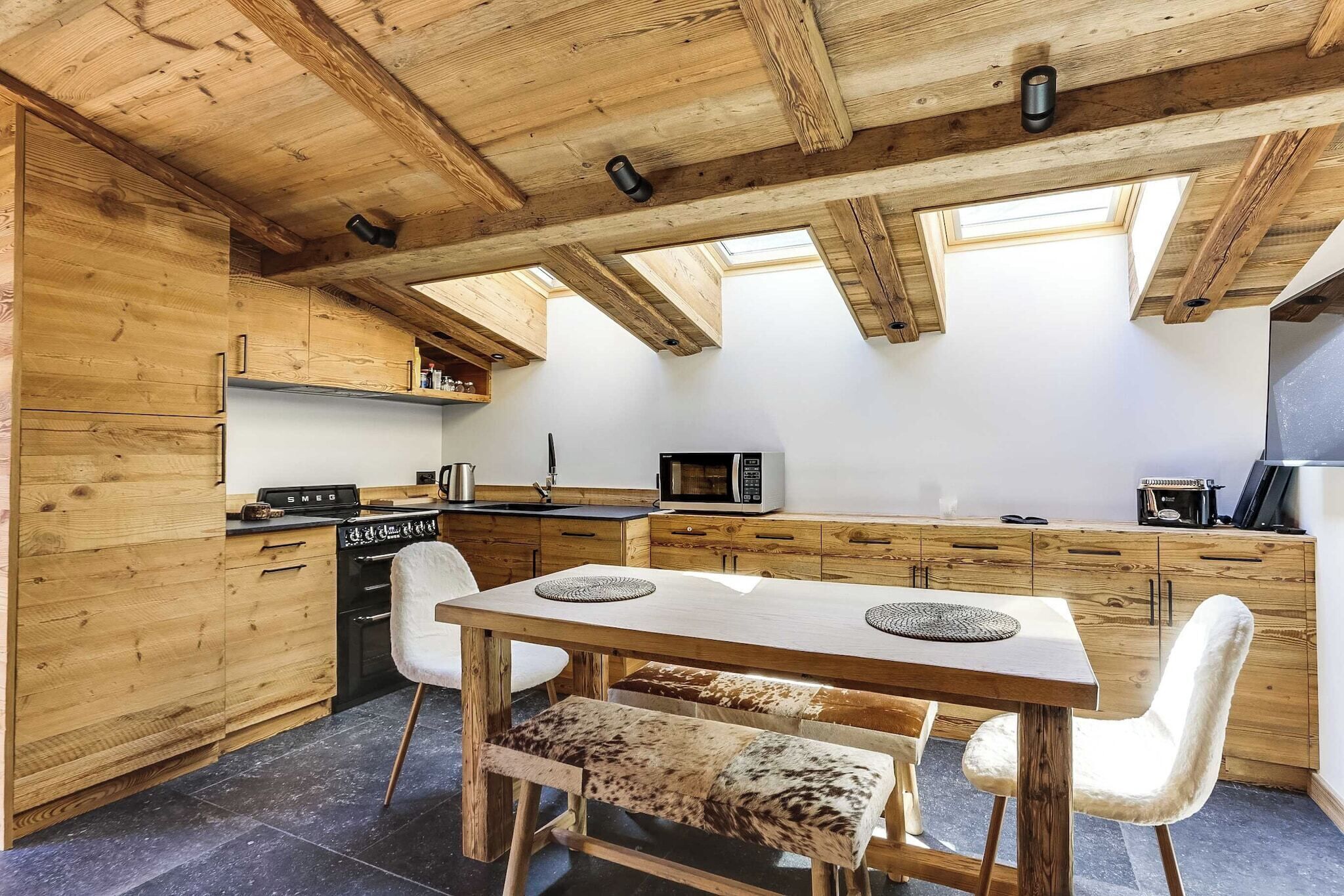Un intérieur en bois comprenant une table à manger, des chaises et un coin cuisine équipé d’appareils électroménagers.