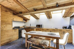 Een houten interieur met een eettafel, stoelen en een keuken met inbouwapparatuur.