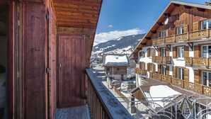 Un edificio de madera con balcones, un techo cubierto de nieve y vistas a la montaña.